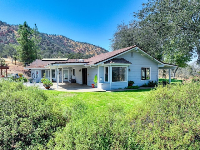 rear view of property featuring a lawn, a patio, and a mountain view