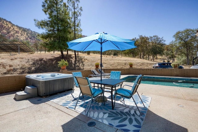 view of patio featuring a swimming pool with hot tub and a mountain view