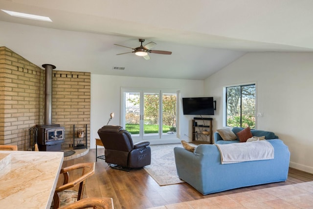 living room with ceiling fan, hardwood / wood-style flooring, lofted ceiling, and a wood stove