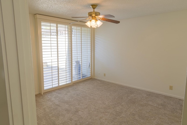 empty room with a ceiling fan, carpet flooring, a textured ceiling, and baseboards