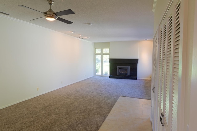 unfurnished living room with carpet, a fireplace with raised hearth, visible vents, ornamental molding, and a textured ceiling