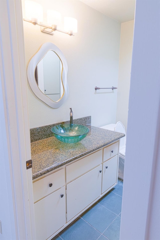 half bath featuring tile patterned flooring, vanity, and toilet