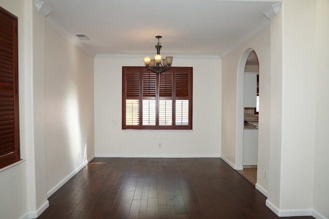 spare room with an inviting chandelier, dark hardwood / wood-style floors, and crown molding