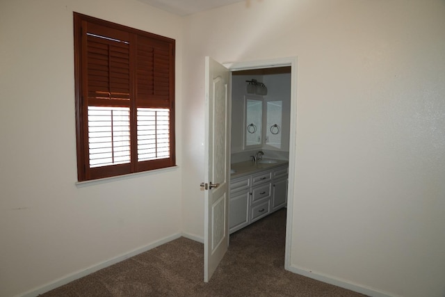 hallway with dark colored carpet and sink