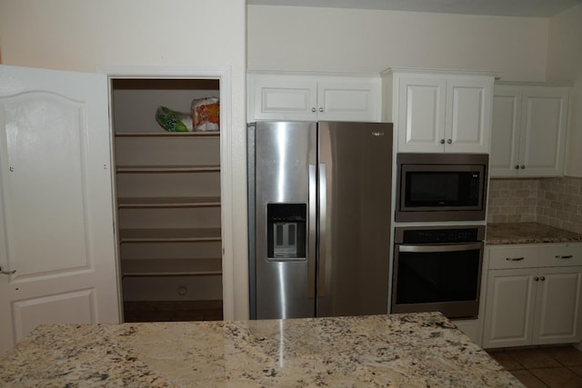 kitchen with stainless steel appliances, white cabinetry, and tasteful backsplash