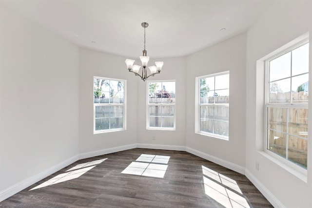 unfurnished dining area with a notable chandelier and dark wood-type flooring