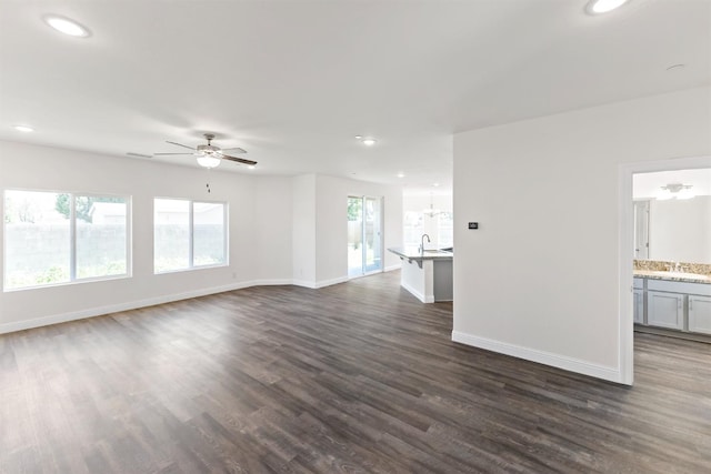 unfurnished living room with ceiling fan with notable chandelier, dark hardwood / wood-style floors, and sink