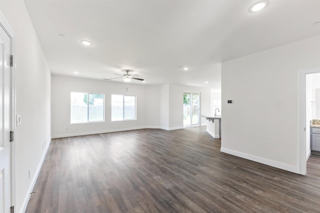 unfurnished living room featuring ceiling fan and dark wood-type flooring