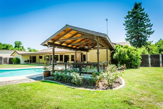 rear view of property with a patio, ceiling fan, and a yard