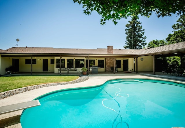 view of pool with a grill, a diving board, a yard, and a patio area