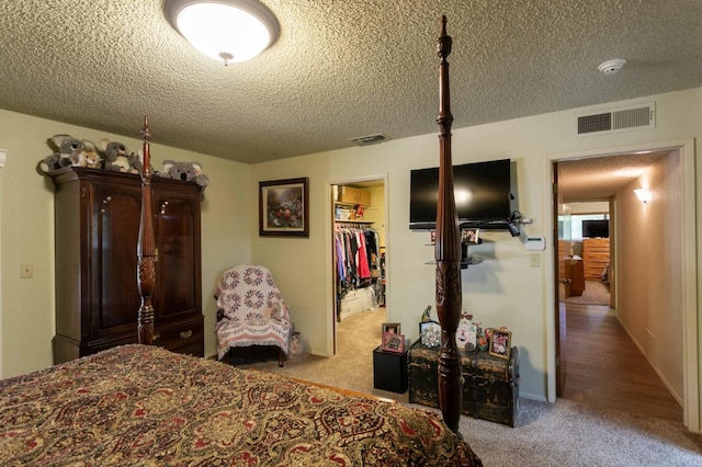 carpeted bedroom featuring a closet, a textured ceiling, and a walk in closet