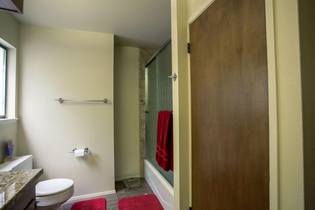 full bathroom with vanity, hardwood / wood-style flooring, a healthy amount of sunlight, bath / shower combo with glass door, and toilet