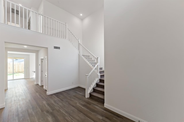 stairway with hardwood / wood-style floors and a towering ceiling