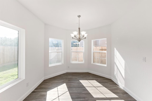 unfurnished dining area featuring a chandelier and dark hardwood / wood-style floors