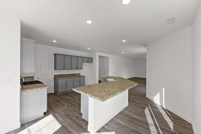 kitchen with gray cabinets, sink, an island with sink, and dark hardwood / wood-style flooring