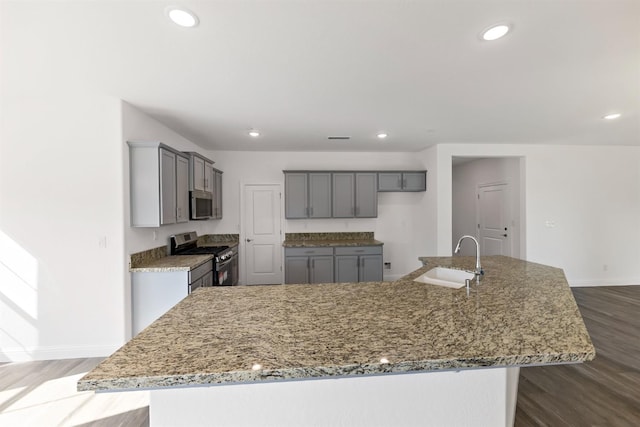 kitchen featuring light stone countertops, appliances with stainless steel finishes, a large island with sink, and sink