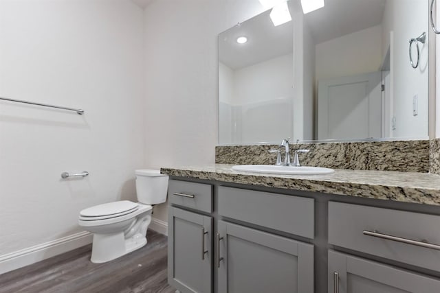 bathroom with walk in shower, hardwood / wood-style floors, vanity, and toilet