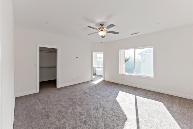 unfurnished bedroom with carpet flooring, ceiling fan, a spacious closet, and a closet