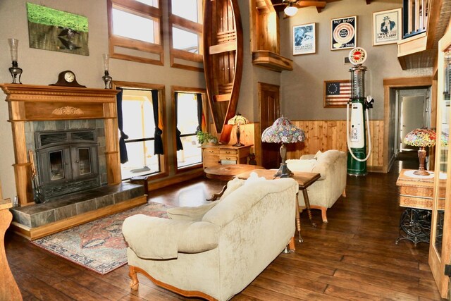 living room with a wainscoted wall, wood walls, a tile fireplace, and a healthy amount of sunlight