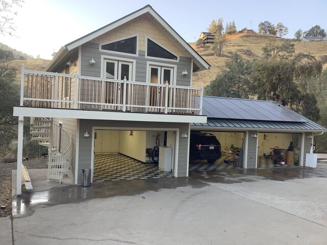 view of front facade with a standing seam roof, driveway, metal roof, an attached garage, and stairway