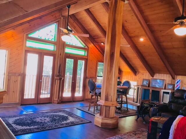 living room featuring vaulted ceiling with beams, wooden ceiling, wood walls, and french doors
