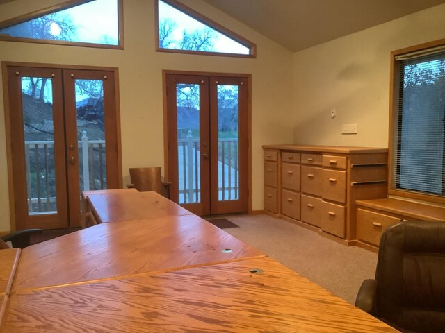 interior space with lofted ceiling, french doors, and light colored carpet