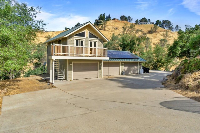 chalet / cabin featuring stairway, solar panels, driveway, a porch, and metal roof
