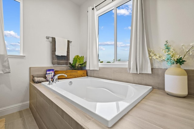 bathroom with hardwood / wood-style floors, plenty of natural light, and a relaxing tiled tub