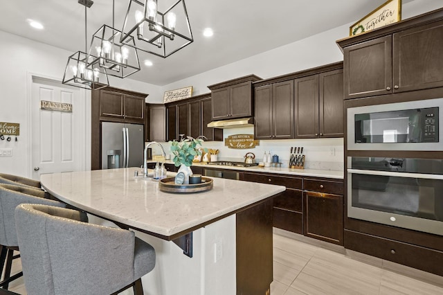 kitchen with appliances with stainless steel finishes, pendant lighting, a center island with sink, sink, and a chandelier