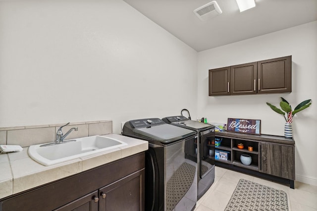 clothes washing area with light tile patterned floors, cabinets, sink, and washing machine and dryer