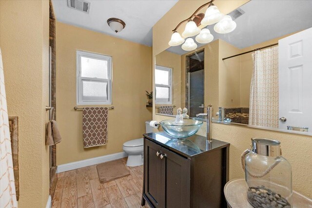 bathroom with hardwood / wood-style floors, vanity, toilet, and a chandelier