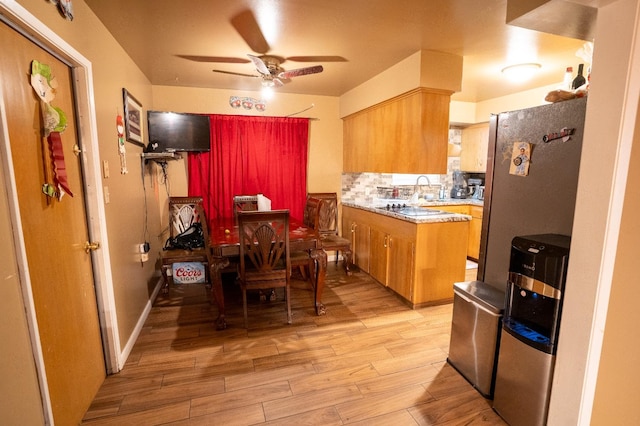 kitchen with ceiling fan, light wood-type flooring, and decorative backsplash