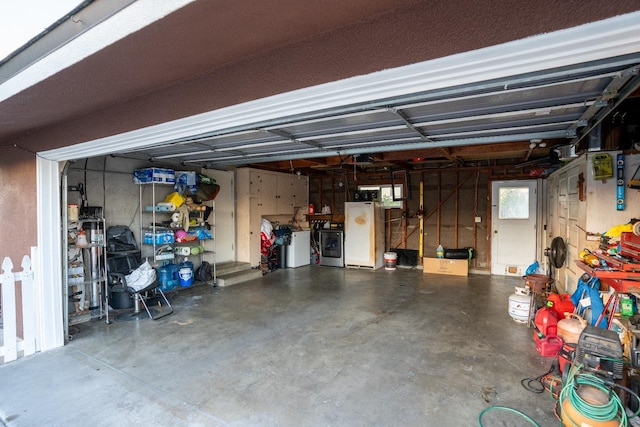 garage with independent washer and dryer and white refrigerator