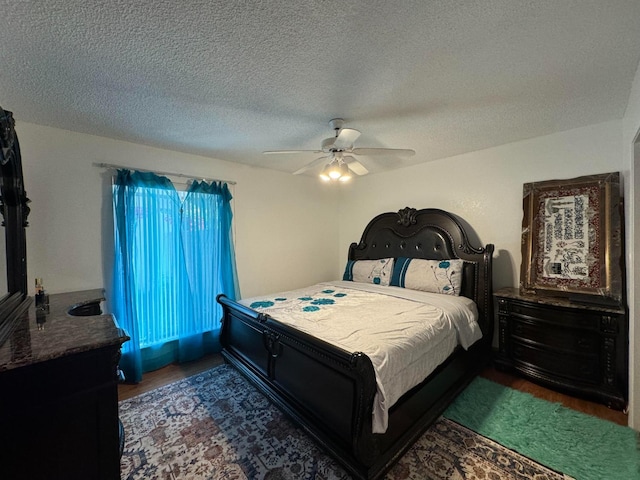 bedroom featuring dark hardwood / wood-style flooring, ceiling fan, and a textured ceiling