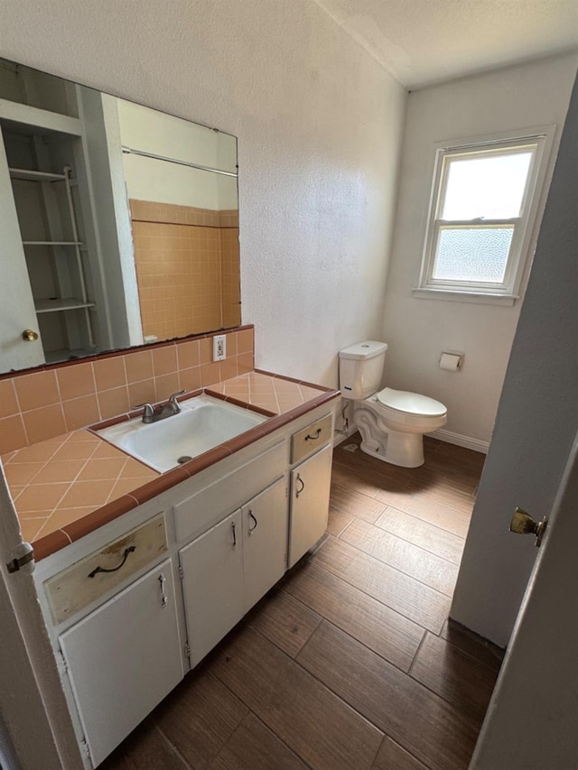 bathroom with vanity, hardwood / wood-style floors, toilet, and decorative backsplash