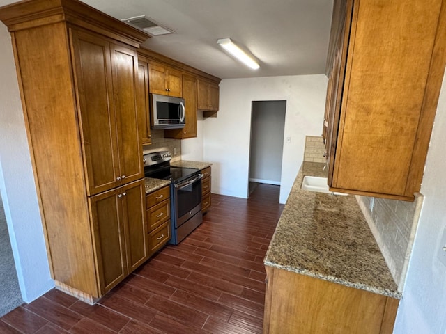 kitchen with stainless steel appliances, light stone counters, dark hardwood / wood-style floors, and backsplash