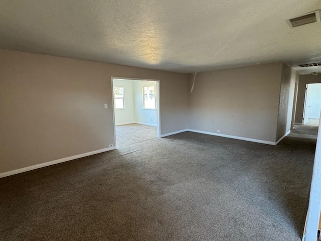 empty room featuring a textured ceiling and dark colored carpet