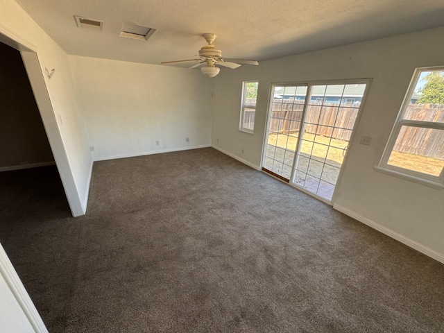 unfurnished room featuring dark carpet, ceiling fan, and a textured ceiling