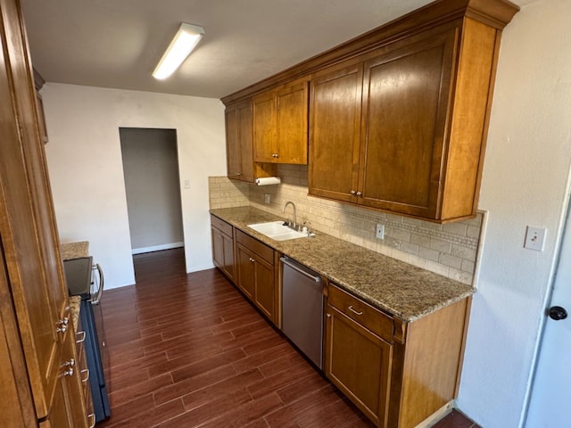 kitchen with dishwasher, dark wood-type flooring, sink, stove, and dark stone countertops