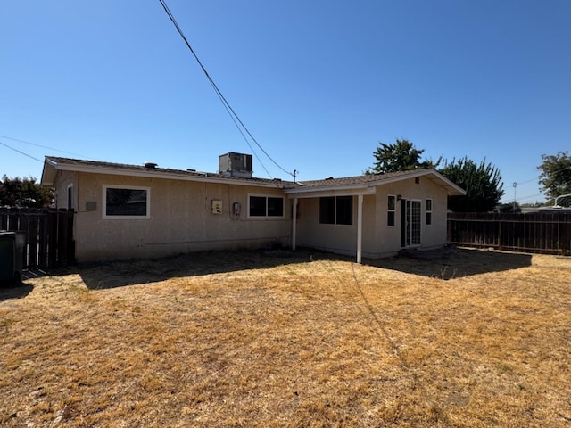 rear view of house featuring a lawn and central AC