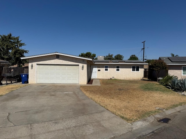 ranch-style home with solar panels, a front yard, and a garage