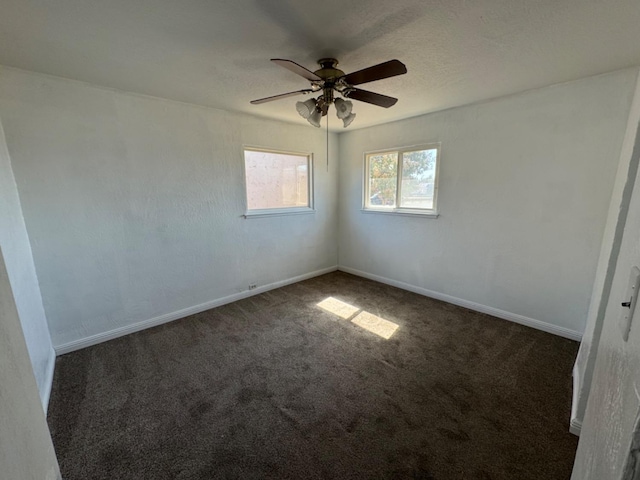 empty room featuring ceiling fan and dark colored carpet