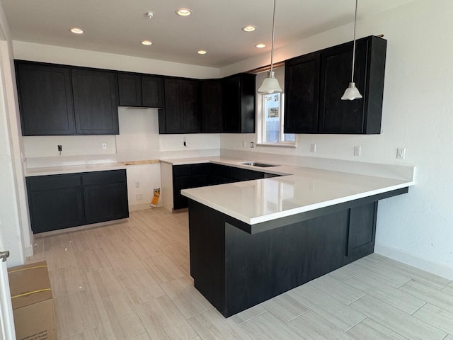 kitchen with kitchen peninsula, light wood-type flooring, and pendant lighting