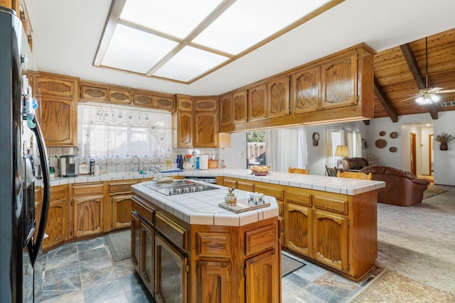 kitchen with lofted ceiling with beams, kitchen peninsula, tile countertops, a center island, and plenty of natural light