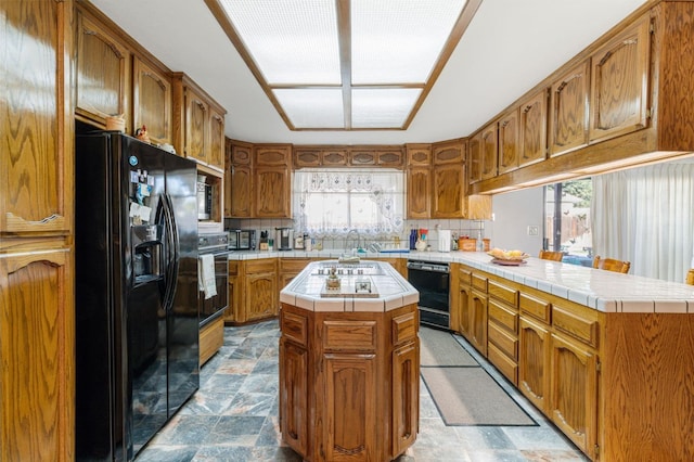 kitchen featuring black appliances, backsplash, a healthy amount of sunlight, and a kitchen island