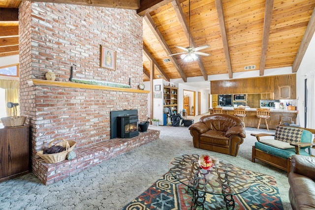 carpeted living room with a wood stove, beam ceiling, high vaulted ceiling, ceiling fan, and wooden ceiling