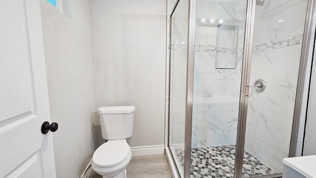 bathroom featuring vanity, hardwood / wood-style flooring, a shower with shower door, and toilet