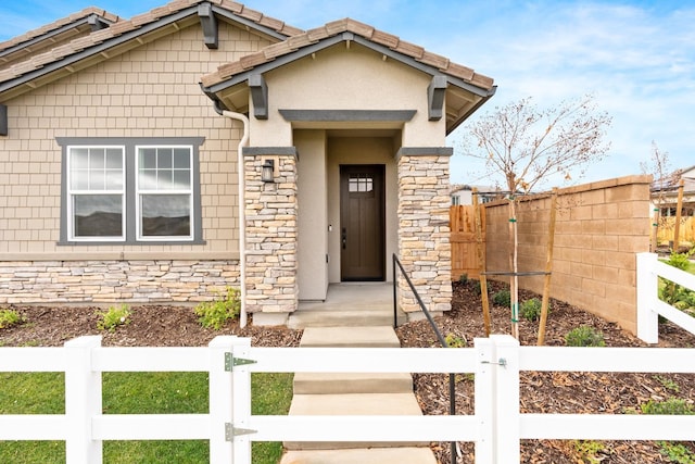 285 S Huckleberry Ln S, S, CA 93636 - view of front facade with stone siding, a gate, a fenced front yard, and stucco siding