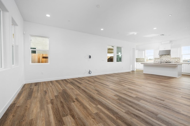 unfurnished living room with plenty of natural light, baseboards, wood finished floors, and recessed lighting