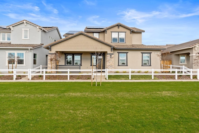 exterior space featuring a fenced front yard, stone siding, a lawn, and solar panels